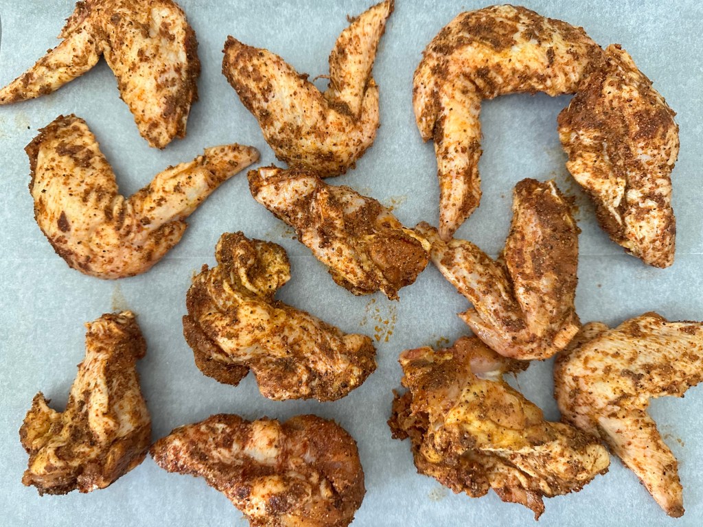 Seasoned chicken wings arranged in an even layer on a baking sheet