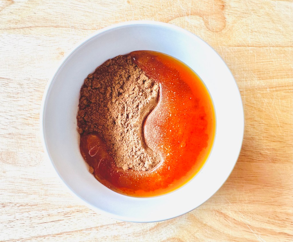A bowl with cinnamon powder, honey, and water being incorporated