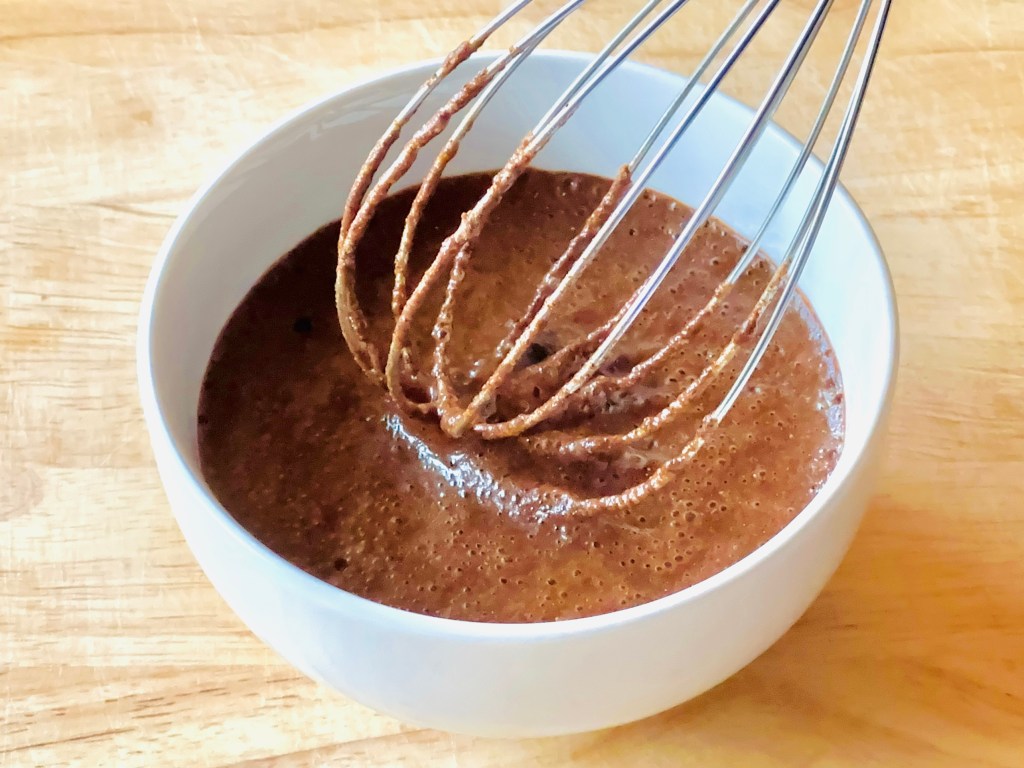 A bowl with a cinnamon, honey, and water mixture being whisked together