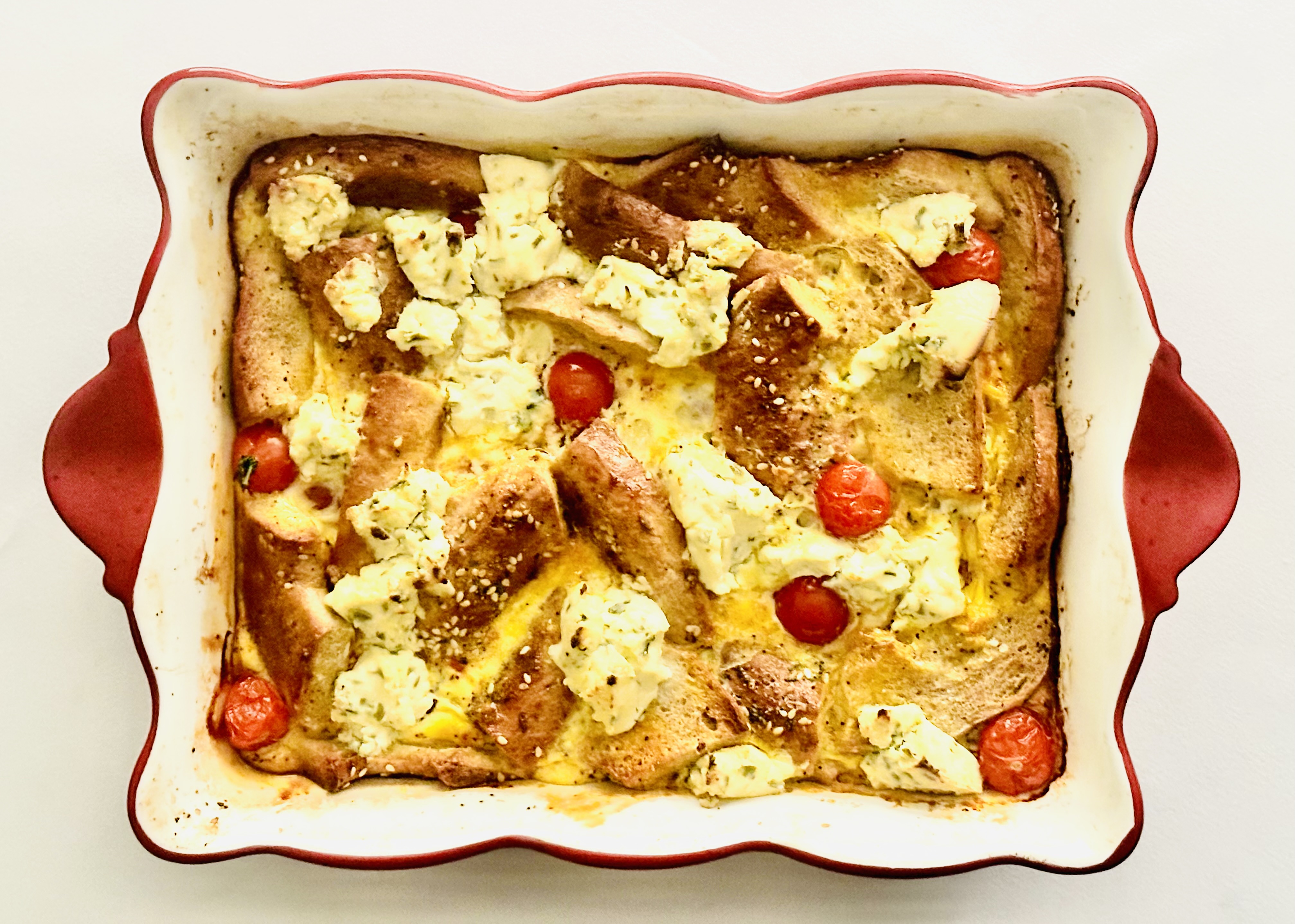 Tray of everything bagel baked with eggs, cheese, and grape tomatoes