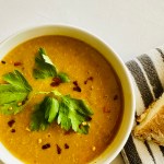 Bowl of yellow lentil soup served alongside crusty bread