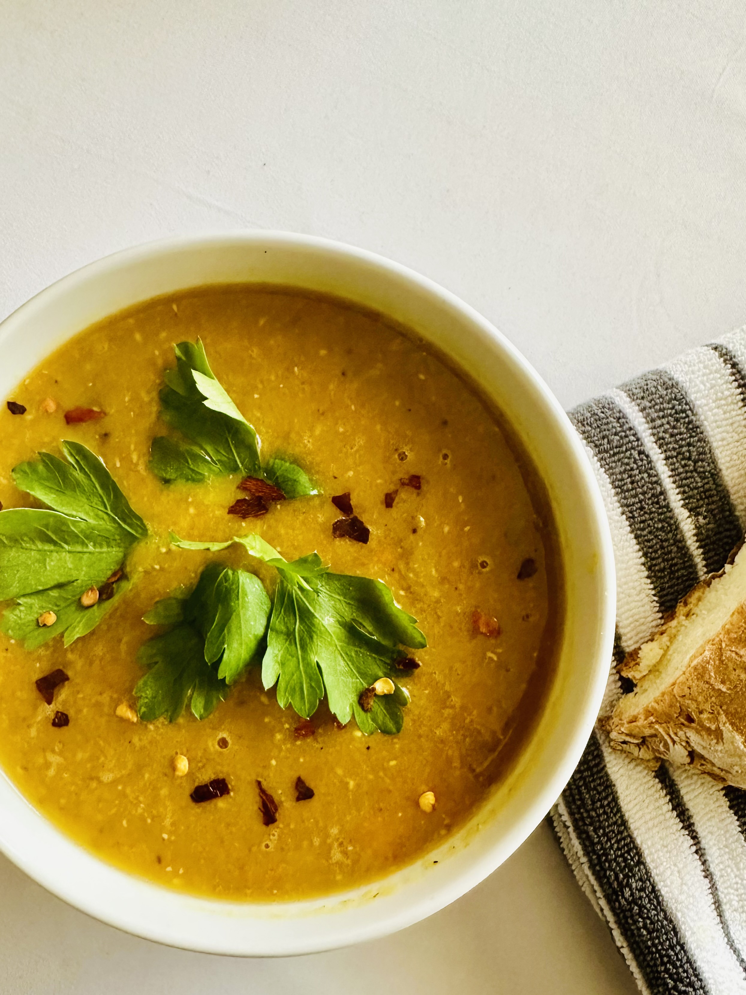 Bowl of yellow lentil soup served alongside crusty bread