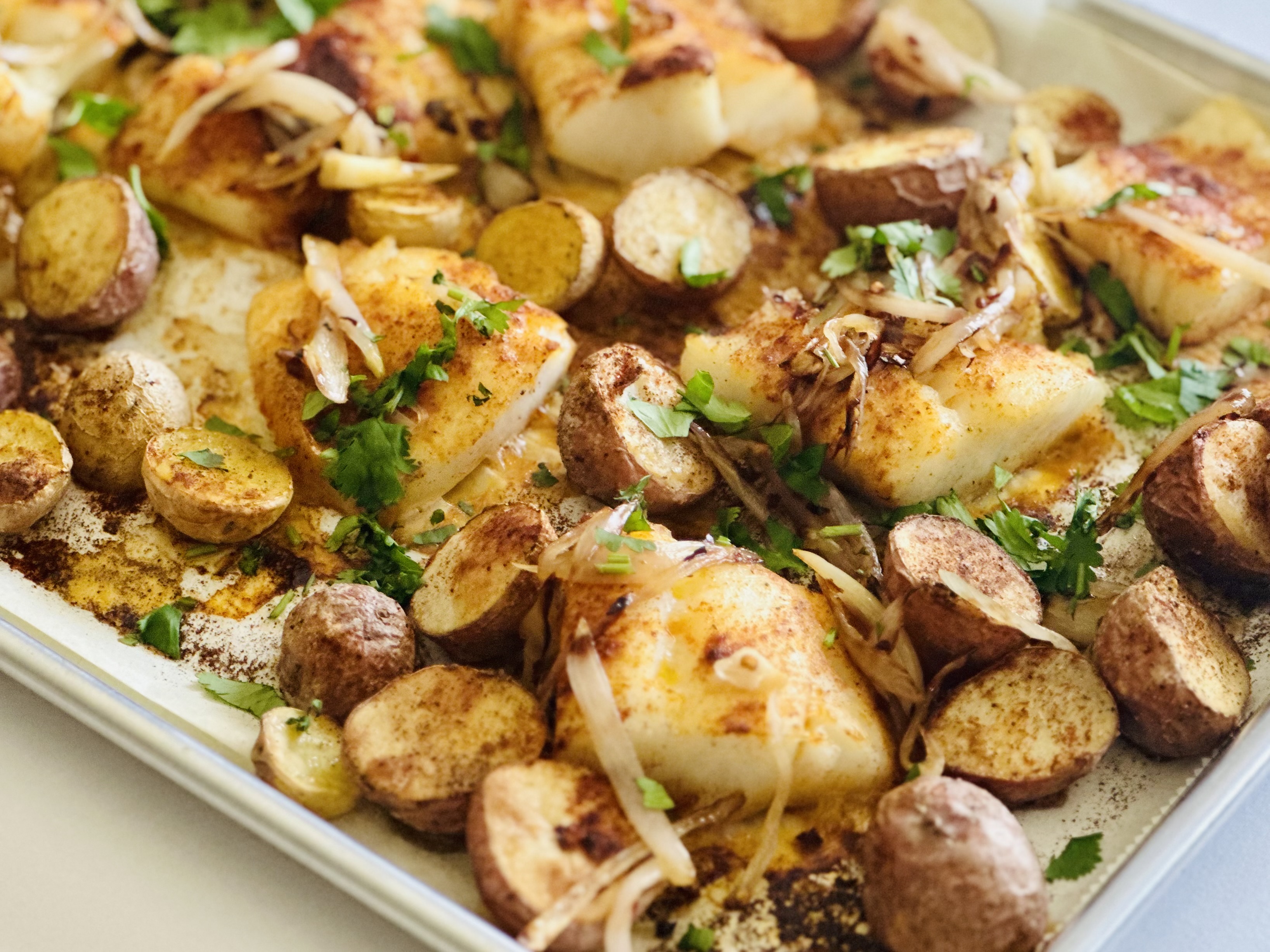 Roasted cod & potatoes on a sheet pan with shallots and garnished with parsley