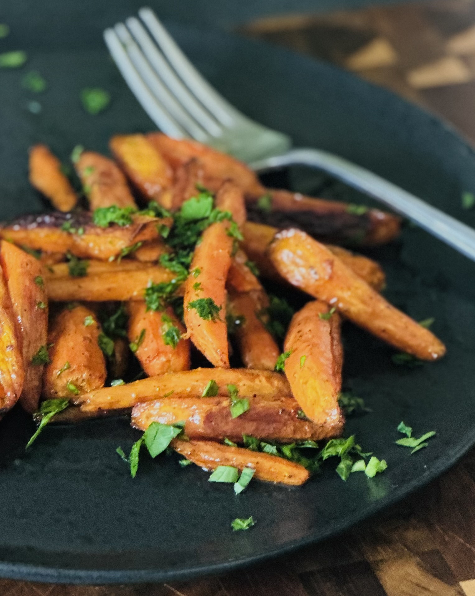 Roasted carrots drizzled with honey-butter glaze on a serving plate with a fork