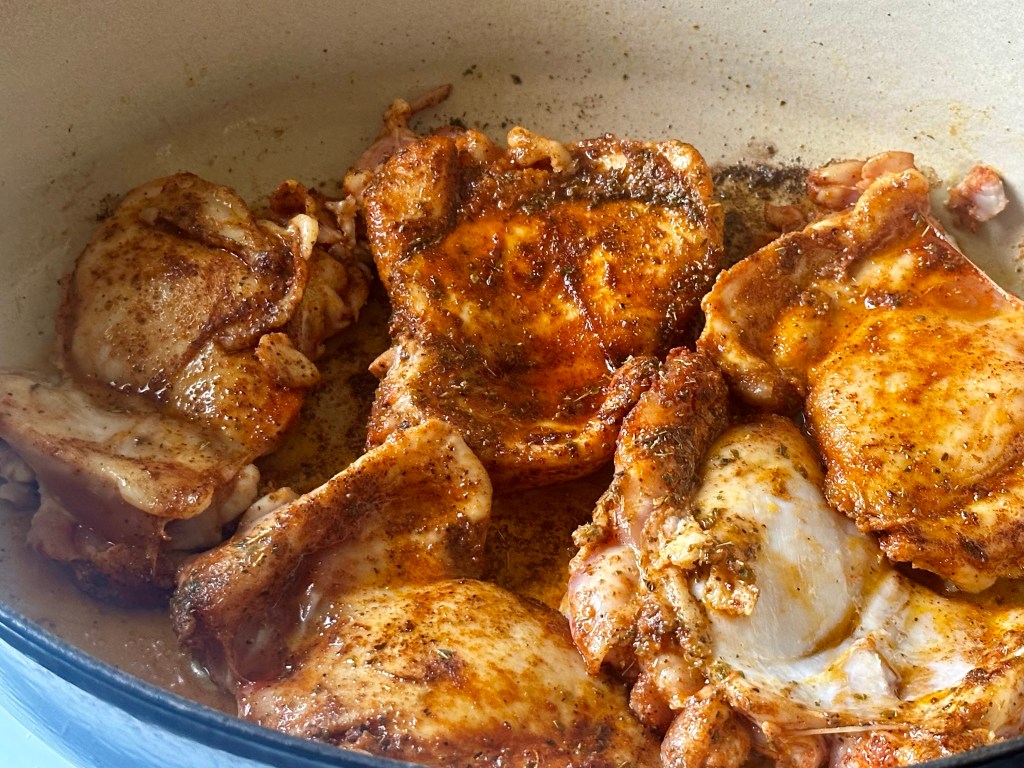 Chicken thighs cooking in a pan