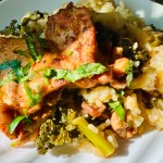 Shot of a plate with a base of rice, kale, and vegetables and baked chicken thighs sitting on top