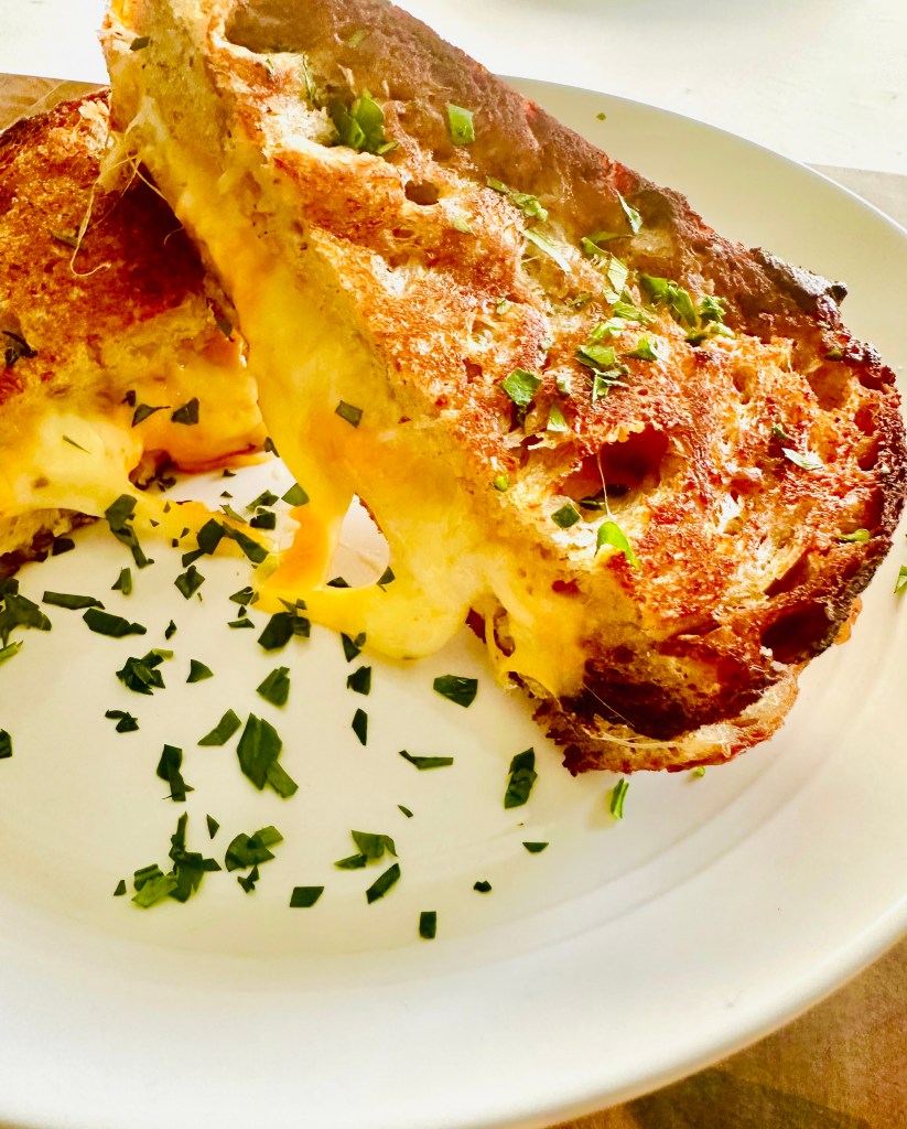 Slices of crisp grilled cheese on a serving plate with parsley for garnish.