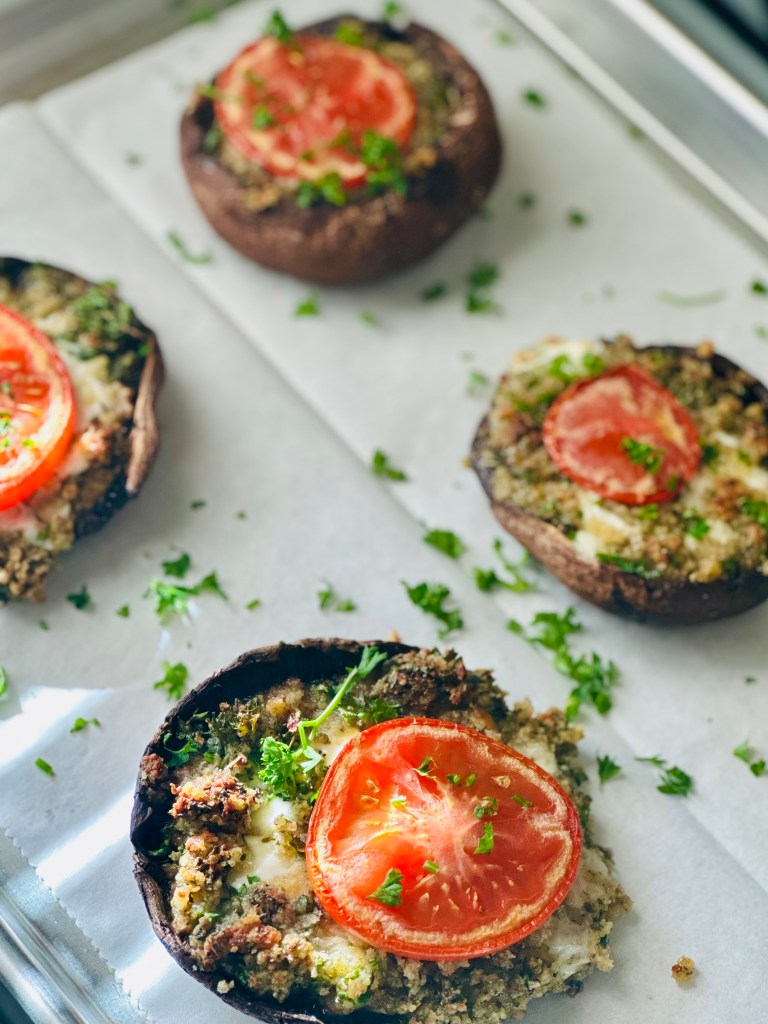 Serving tray of stuffed portobello mushrooms with mozzarella, tomato, parsley, garlic, panko, and Parmesan