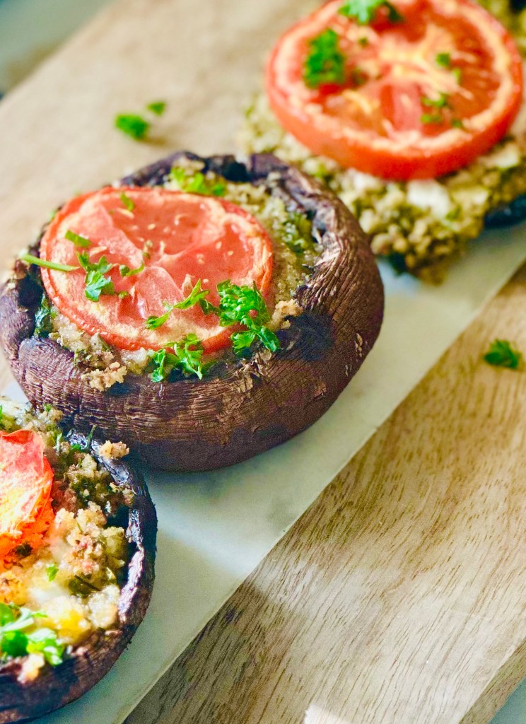 Serving tray of stuffed portobello mushrooms with mozzarella, tomato, parsley, garlic, panko, and Parmesan