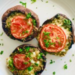 Serving plate of stuffed portobello mushrooms with mozzarella, tomato, parsley, garlic, panko, and Parmesan