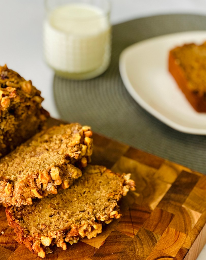 Slices of banana bread on a cutting board with a glass of milk