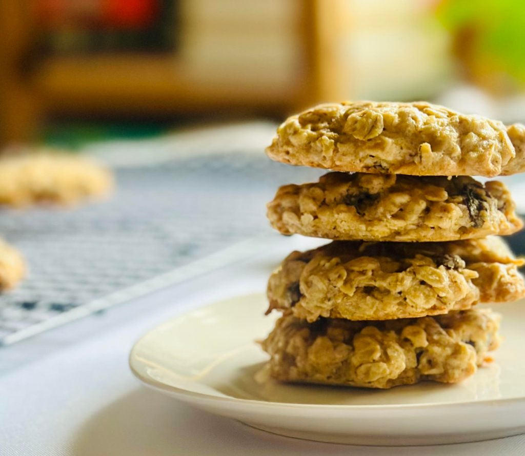 A plate with 4 oatmeal raisin cookies stacked on top of each other