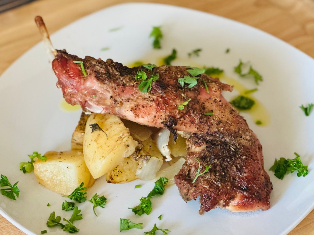 Serving plate of roasted rabbit and potatoes with parsley as garnish