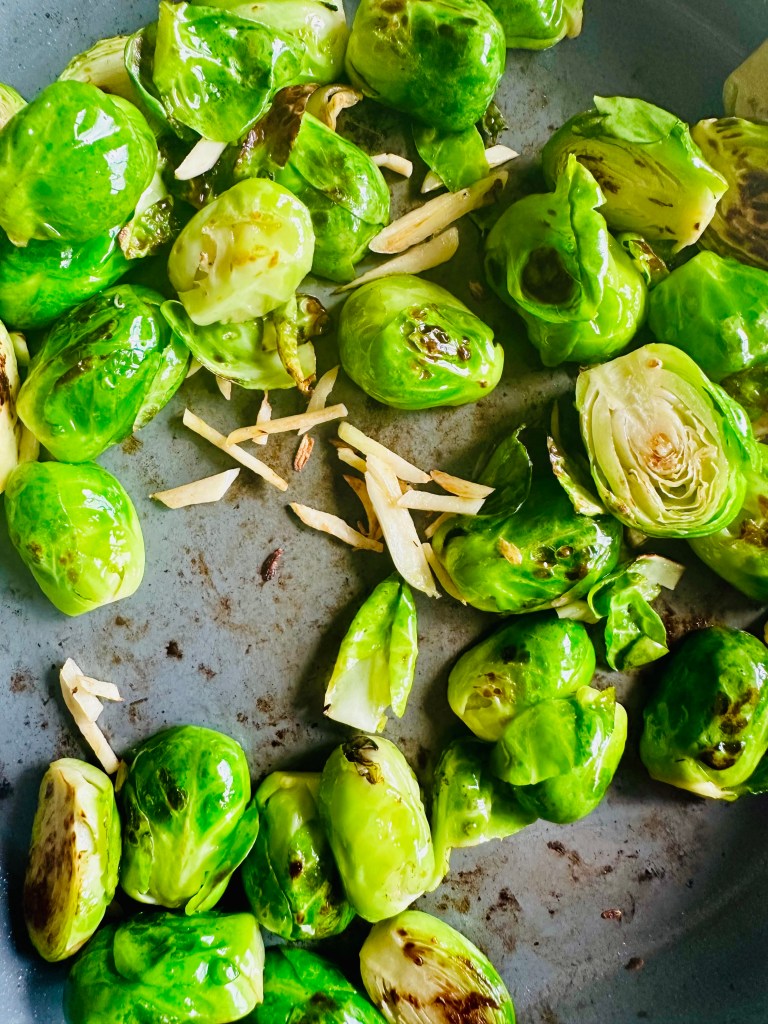 Brussels sprouts being cooked in a pan with garlic
