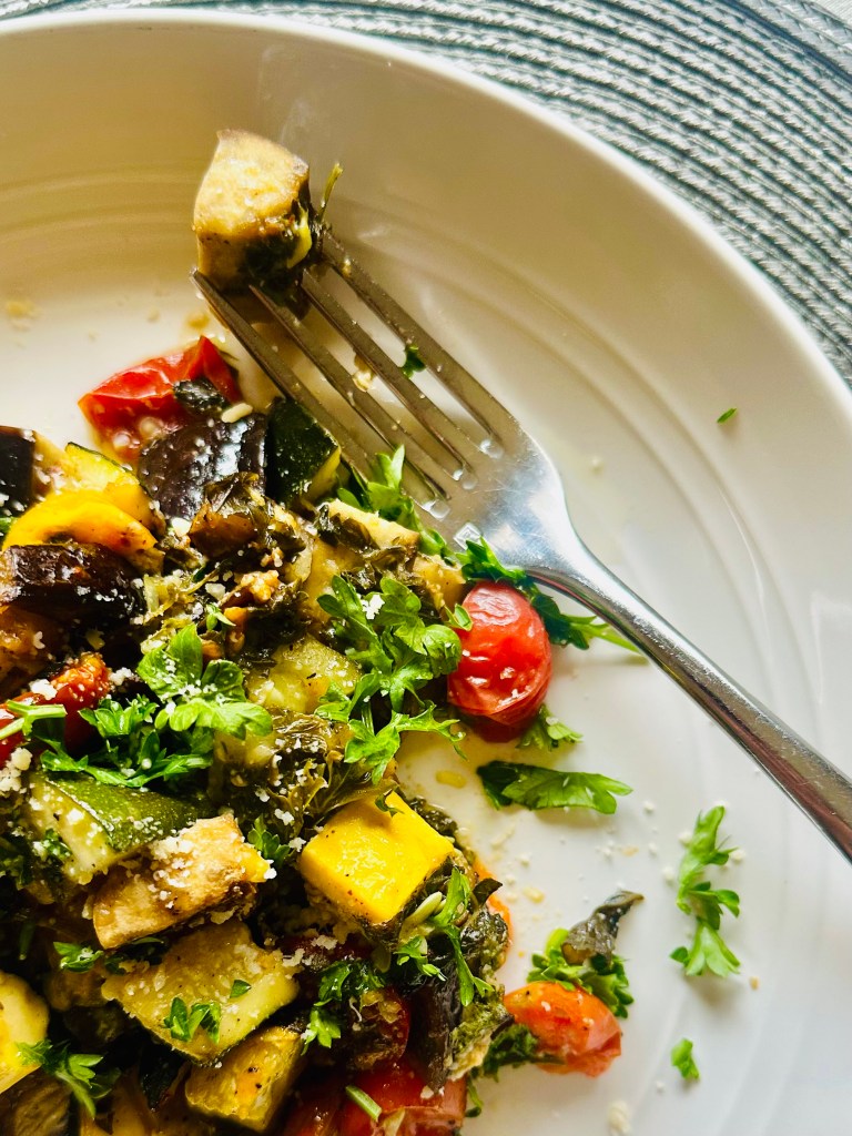 A serving plate and fork with baked eggplant, zucchini, and tomatoes
