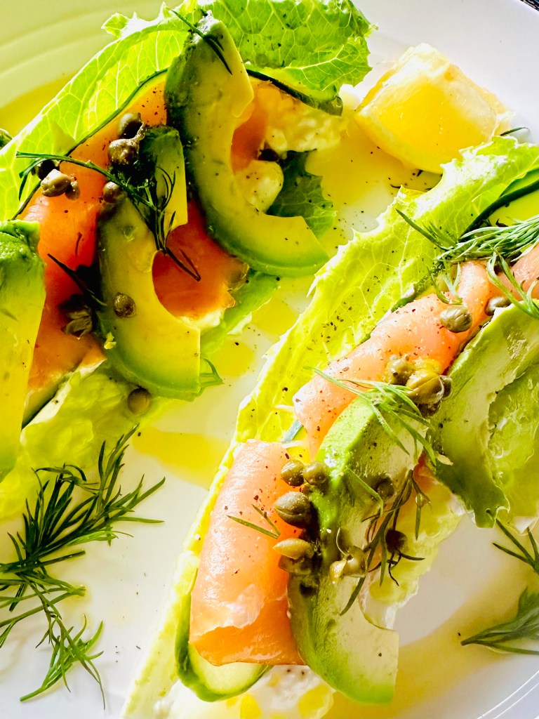 A plate of lettuce wraps with a filling of cottage cheese, smoked salmon, avocado, cucumber, capers, and dill
