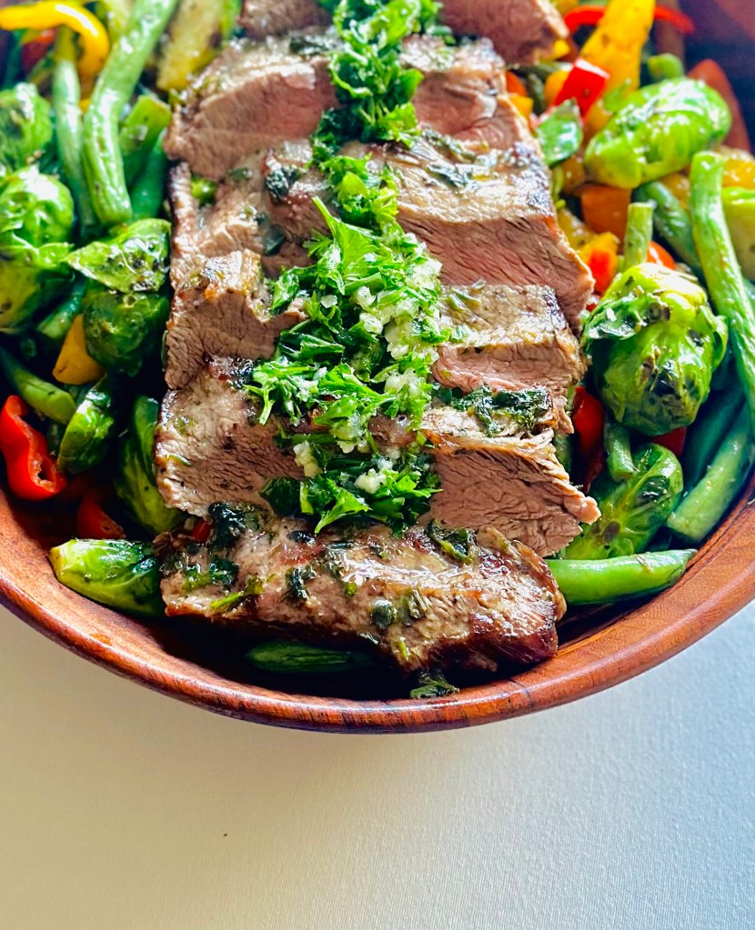 Serving bowl of pan-fried flat iron steak with vegetables