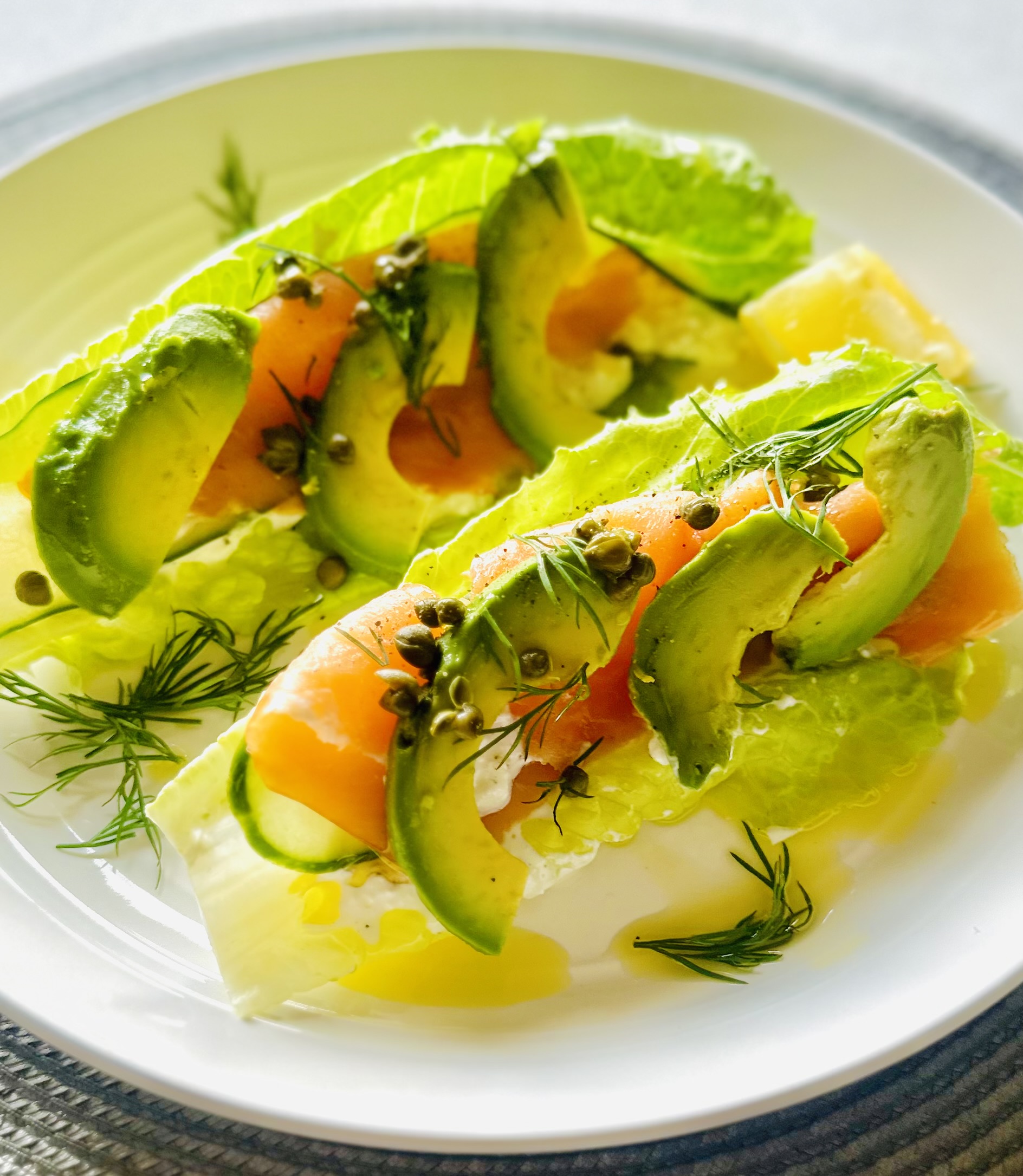 A plate of lettuce wraps with a filling of cottage cheese, smoked salmon, avocado, cucumber, capers, and dill