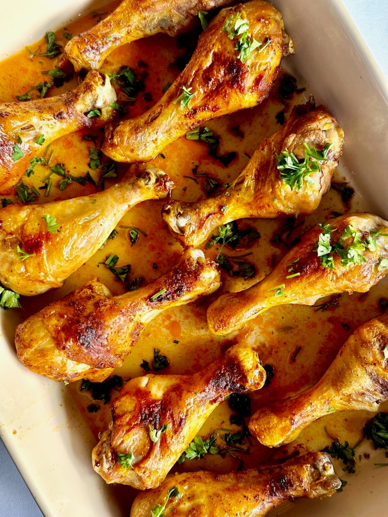 Oven-baked chicken drumsticks garnished with parsley in a baking dish