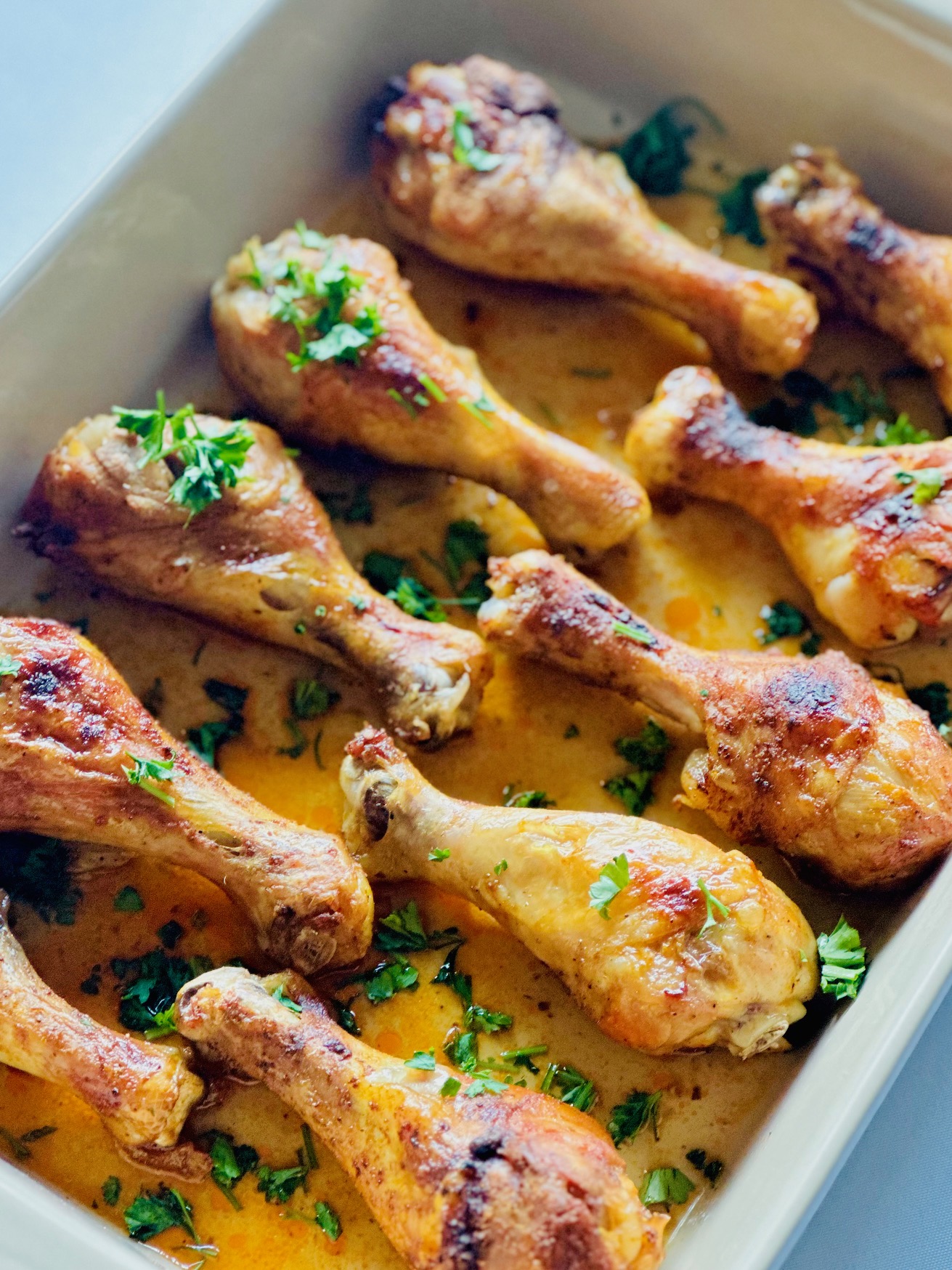 Oven-baked chicken drumsticks garnished with parsley in a baking dish
