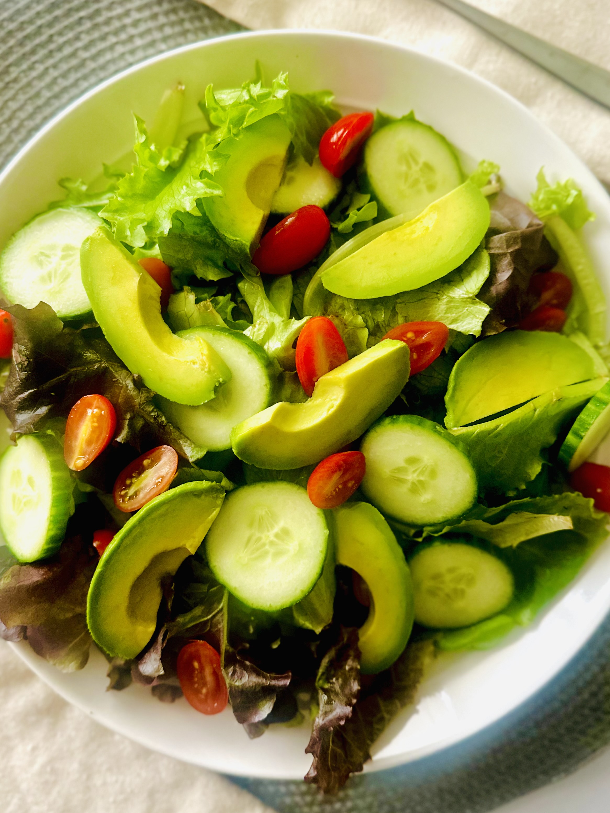 Simple green salad with cucumber, tomatoes, and avocado slices