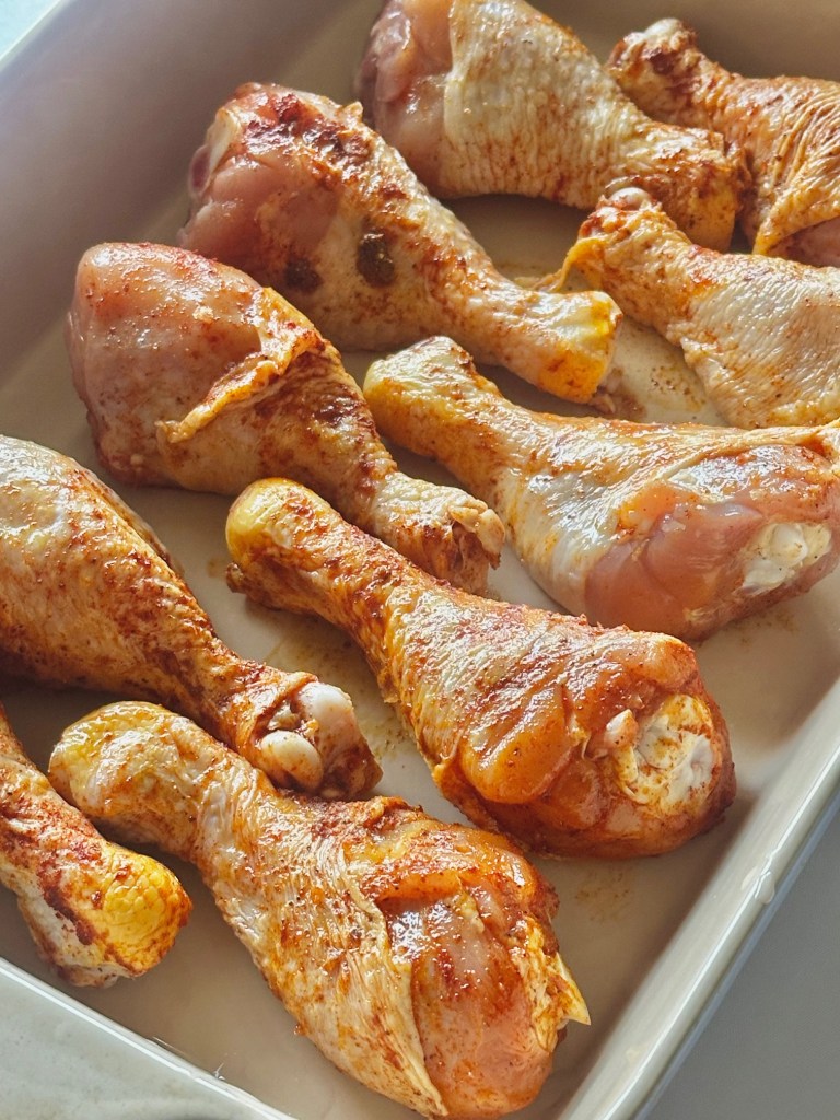 A photo of raw chicken drumsticks seasoned and ready to be baked in the oven