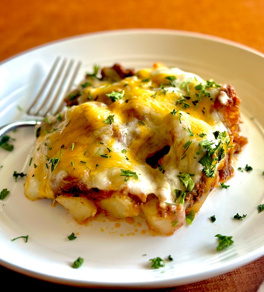 Homemade ground beef and potato casserole with melted cheddar cheese and parsley