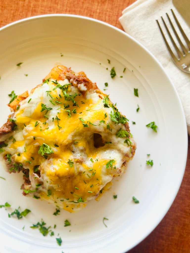 Homemade ground beef and potato casserole with melted cheddar cheese and parsley