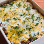 Homemade ground beef and potato casserole with melted cheddar cheese and parsley