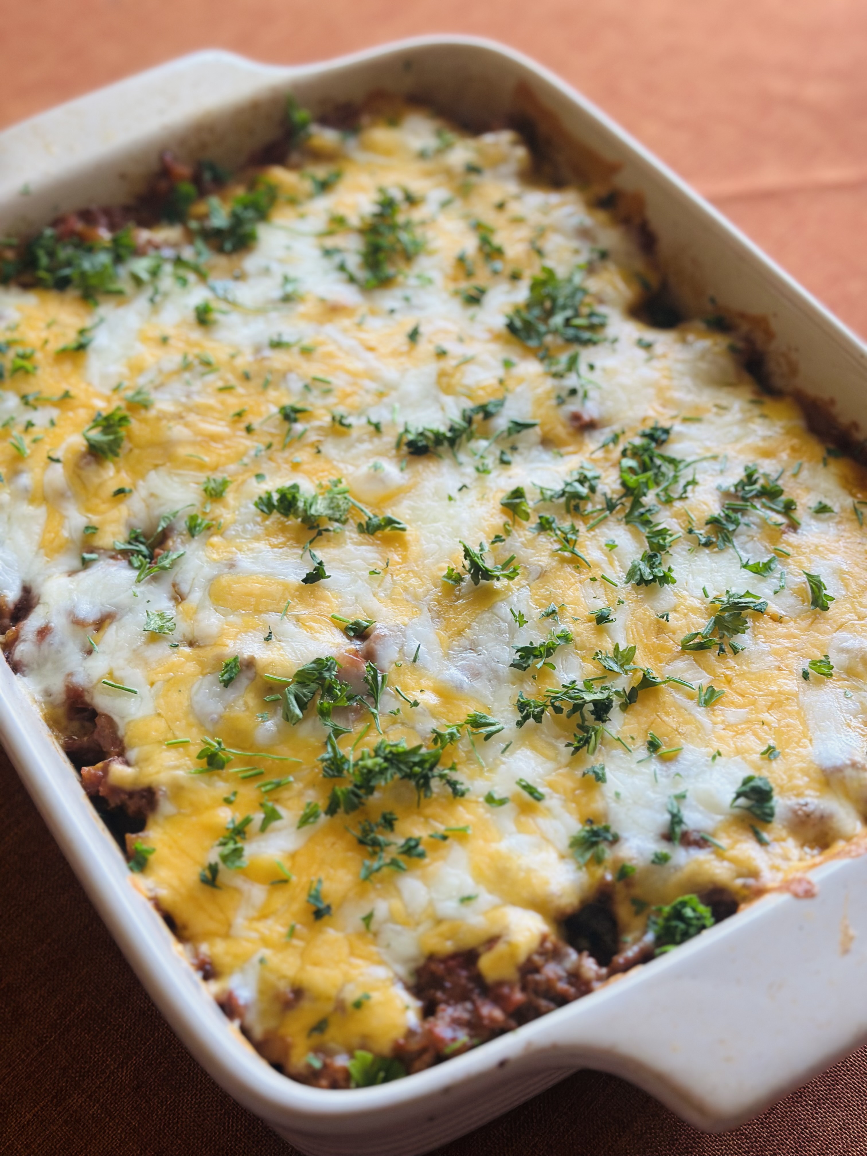 Homemade ground beef and potato casserole with melted cheddar cheese and parsley