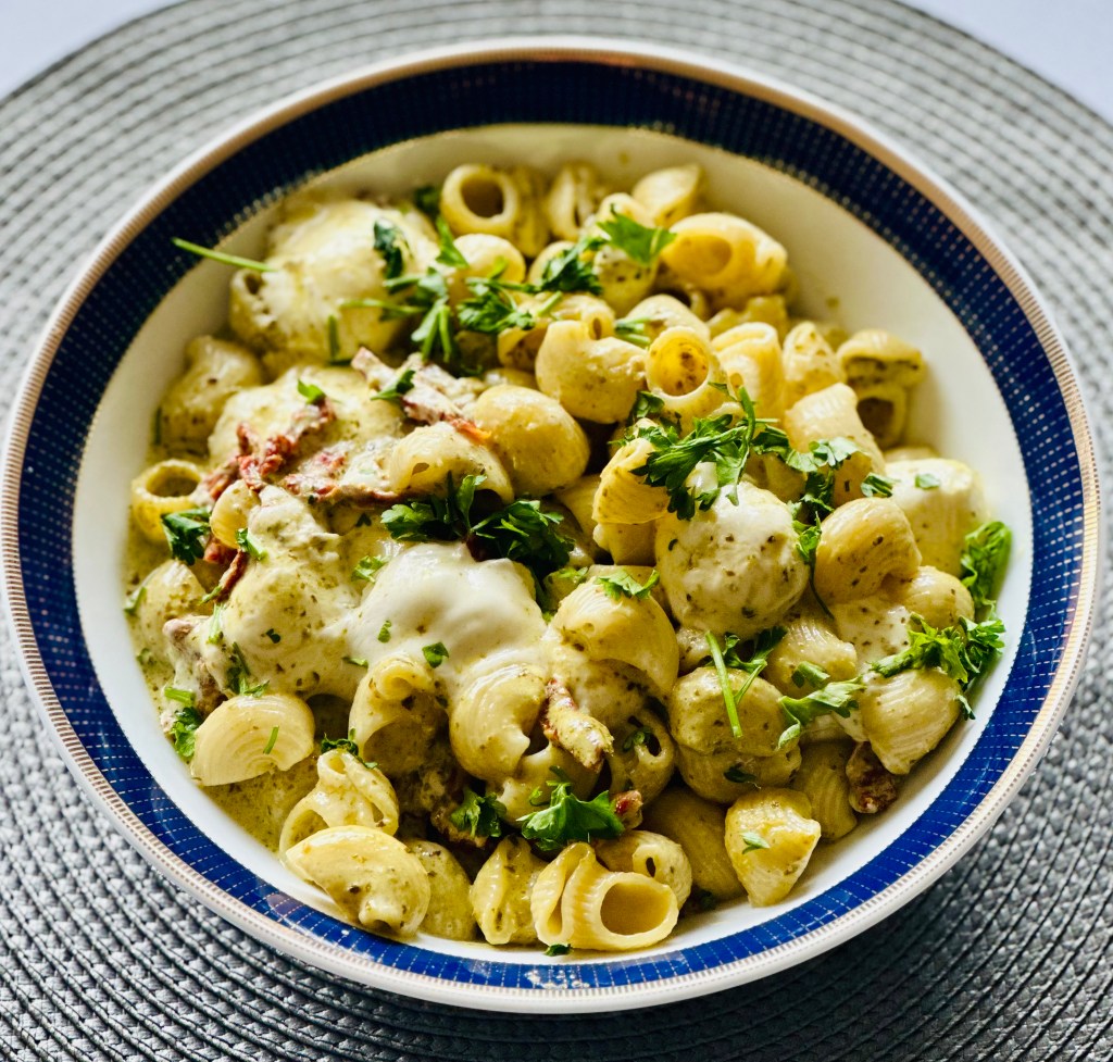 A serving bowl of homemade creamy pesto pasta with mozzarella