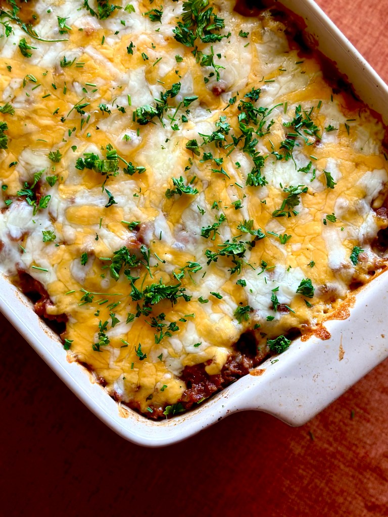 Homemade ground beef and potato casserole with melted cheddar cheese and parsley