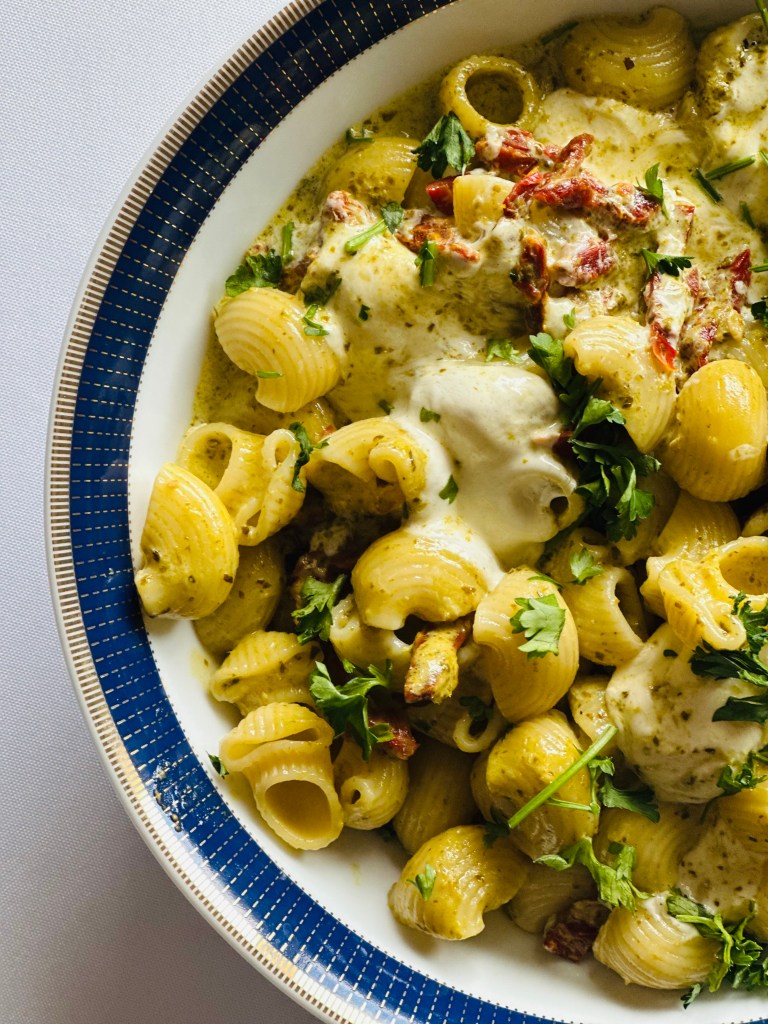 A serving bowl of homemade creamy pesto pasta with mozzarella