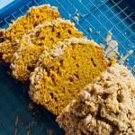 A loaf of pumpkin spice crumb cake on a wire rack topped with pumpkin-spice glaze