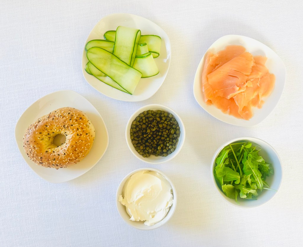 A photo of ingredients used to assemble a smoked salmon bagel sandwich