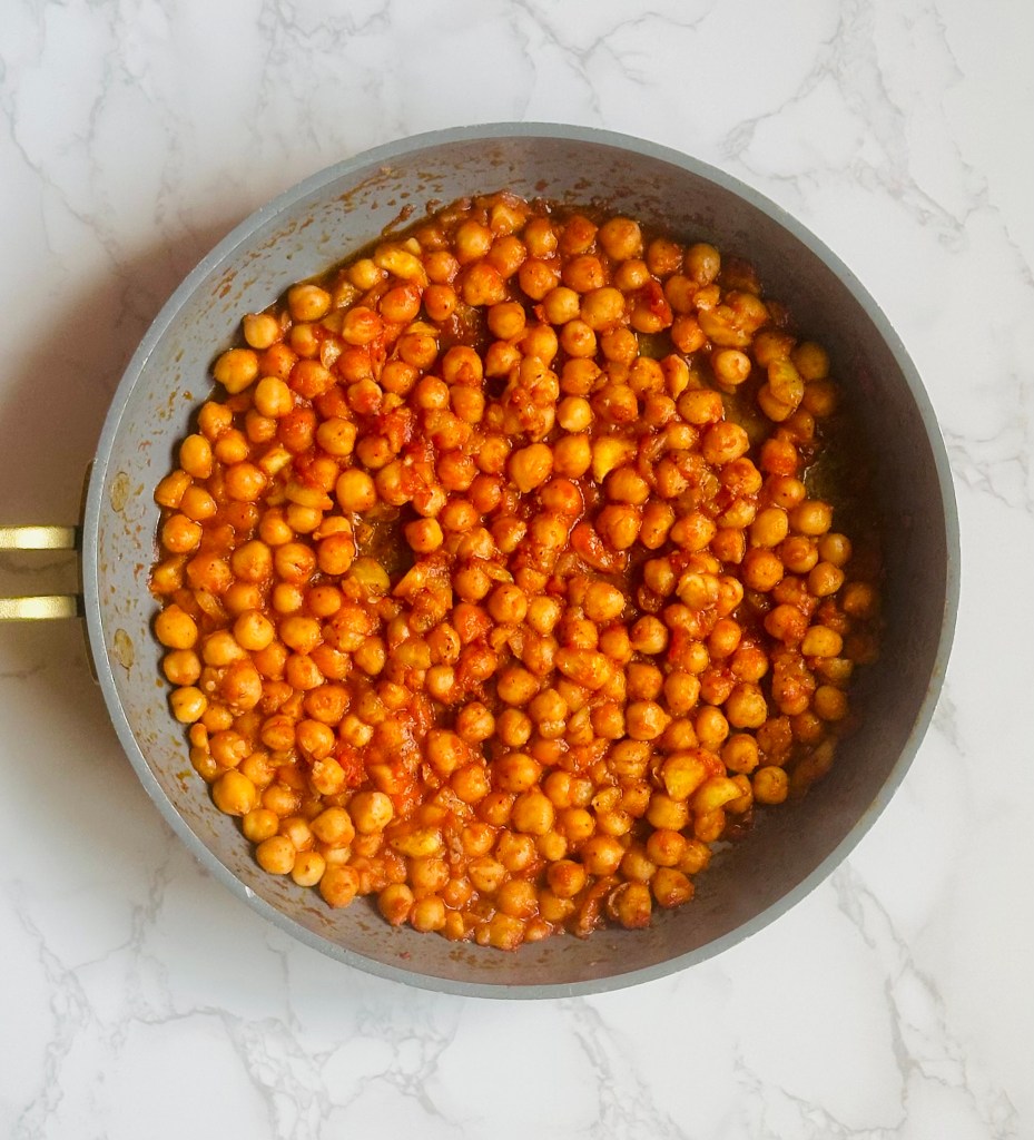 A skillet of chickpeas simmering with crushed tomatoes