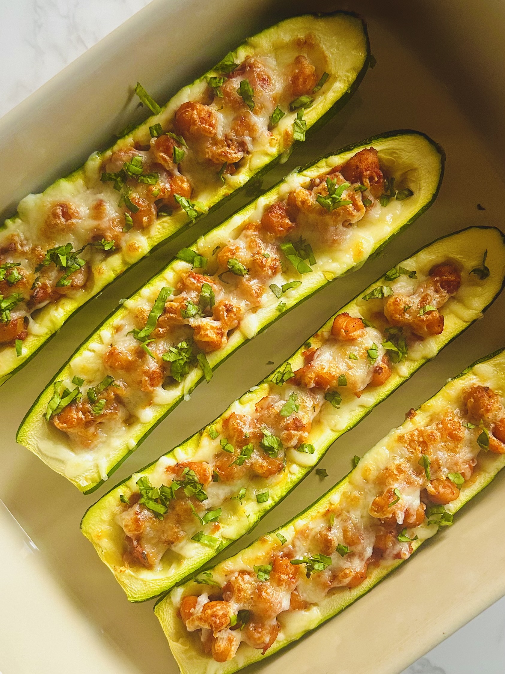 Homemade zucchini boats with chickpeas and tomatoes in a baking dish