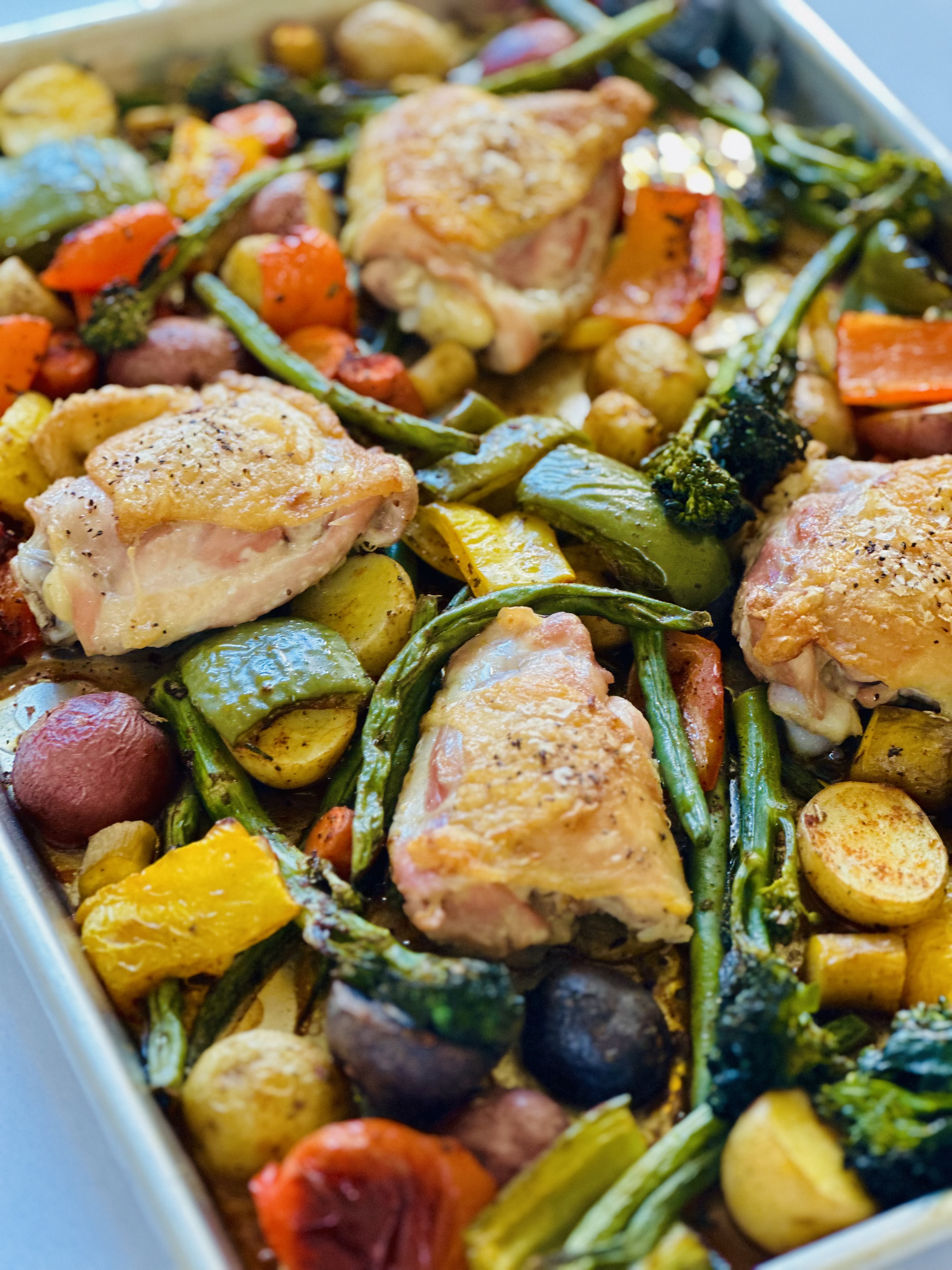 Juicy crisp chicken and roasted rainbow vegetables nestled in a sheet pan