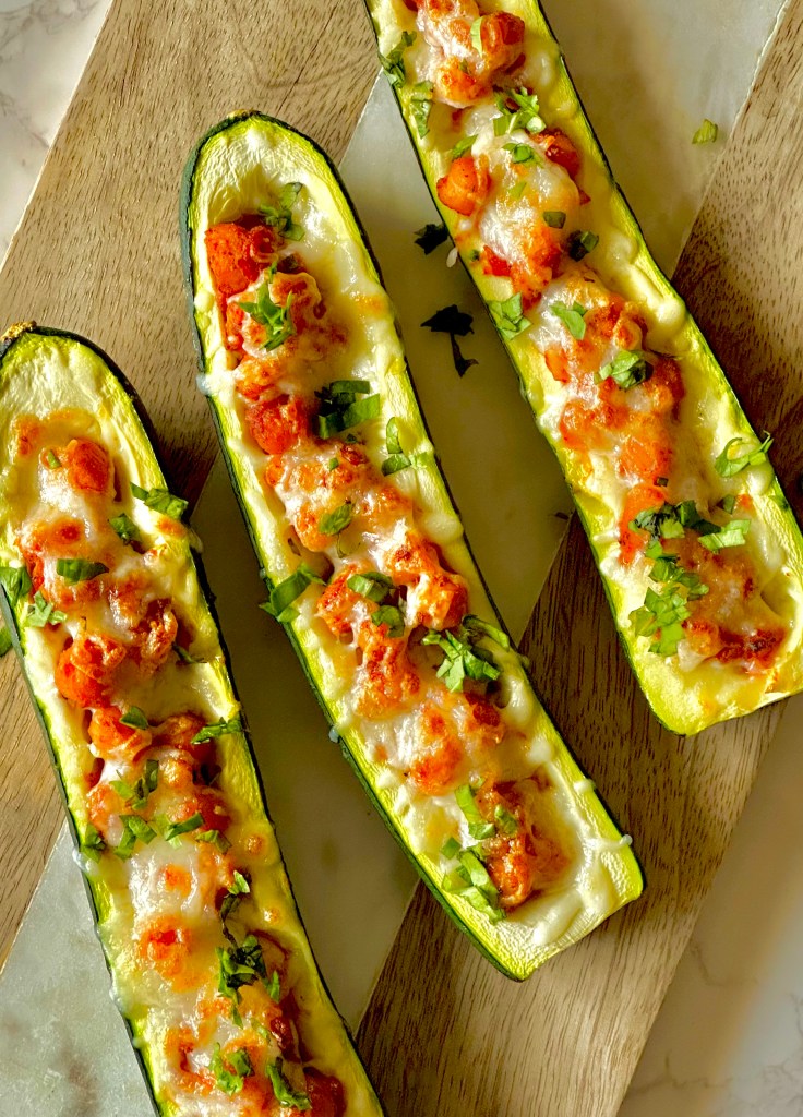 Homemade zucchini boats with chickpeas and tomatoes assembled on a cutting board
