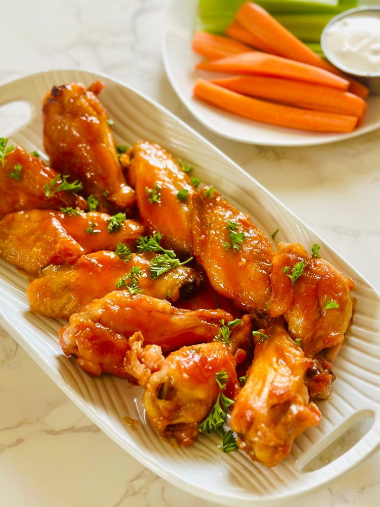 A platter of buffalo chicken wings garnished with chopped parsley
