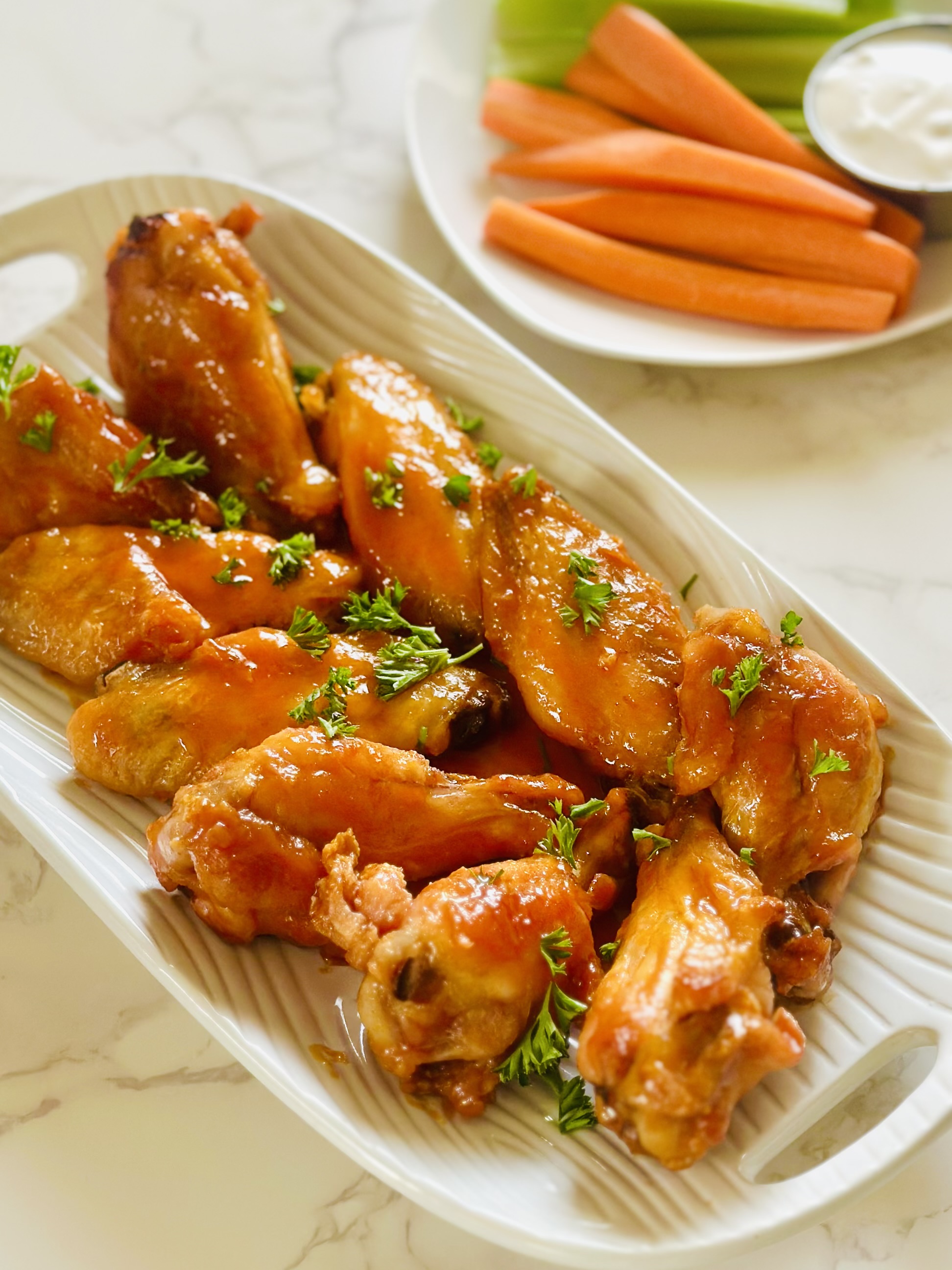 A platter of buffalo chicken wings garnished with chopped parsley
