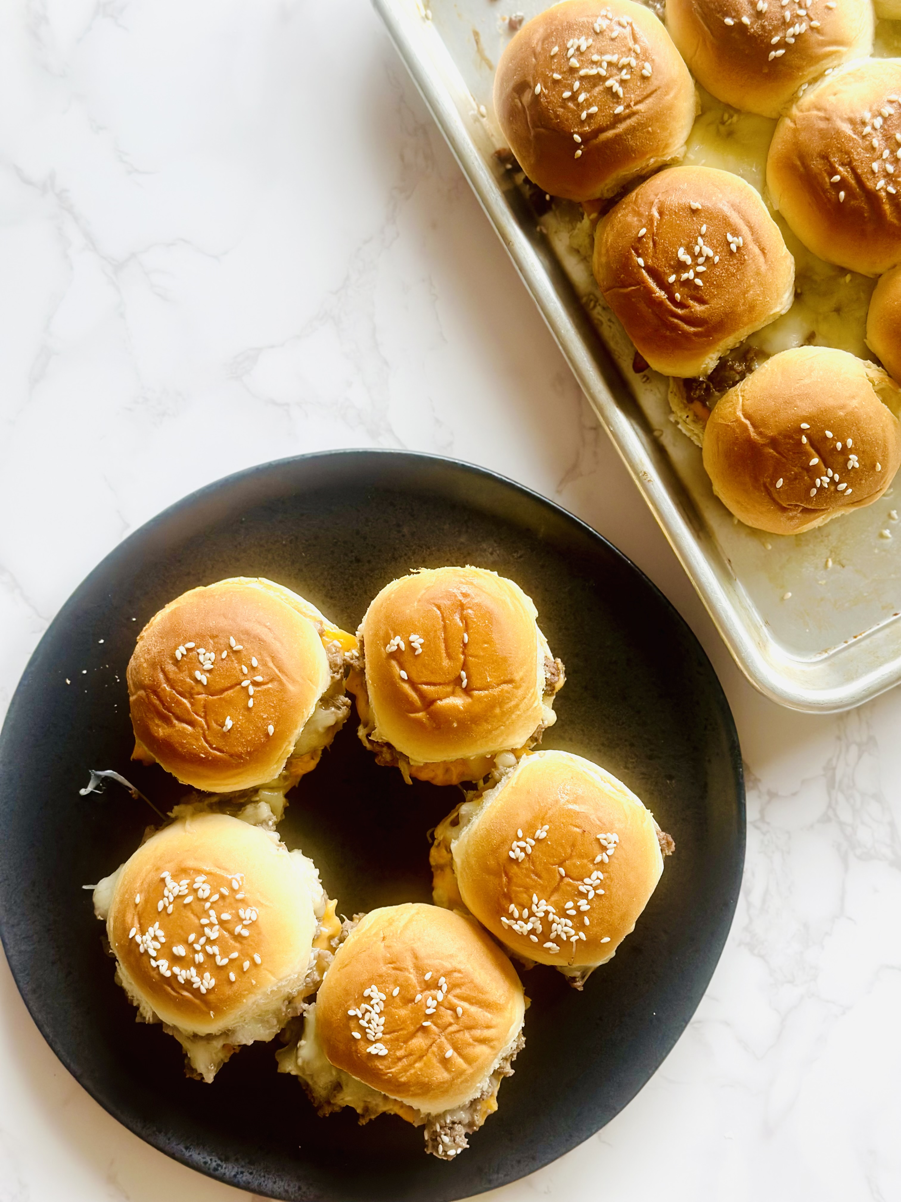 5 cheeseburger sliders on Hawaiian slider buns arranged on a serving plate