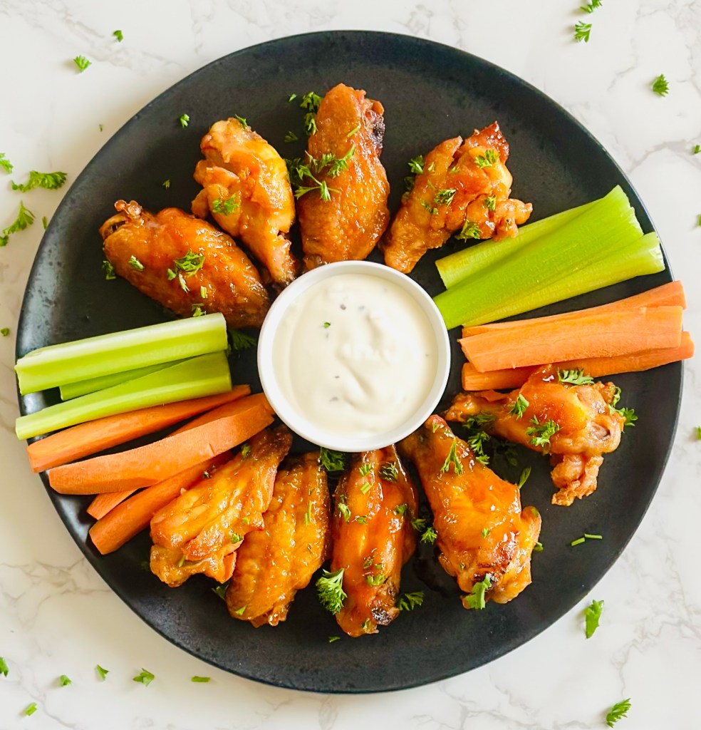 A plate of buffalo chicken wings garnished with chopped parsley