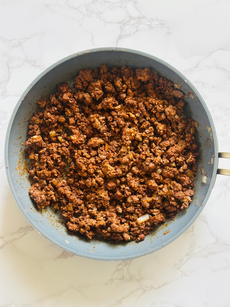 A photo of ground beef and onions in a skillet