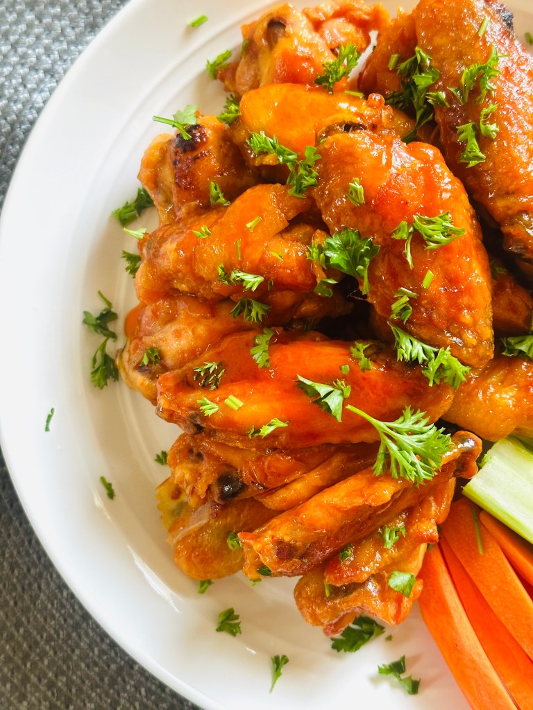 A platter of buffalo chicken wings garnished with chopped parsley