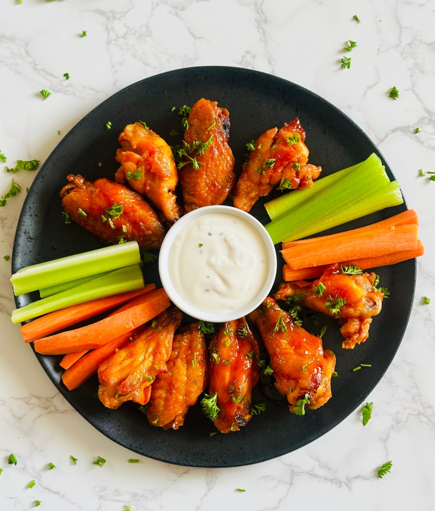 A platter of buffalo chicken wings garnished with chopped parsley