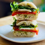 A photo of a roasted pepper, mozzarella, and pesto sandwich on a serving plate