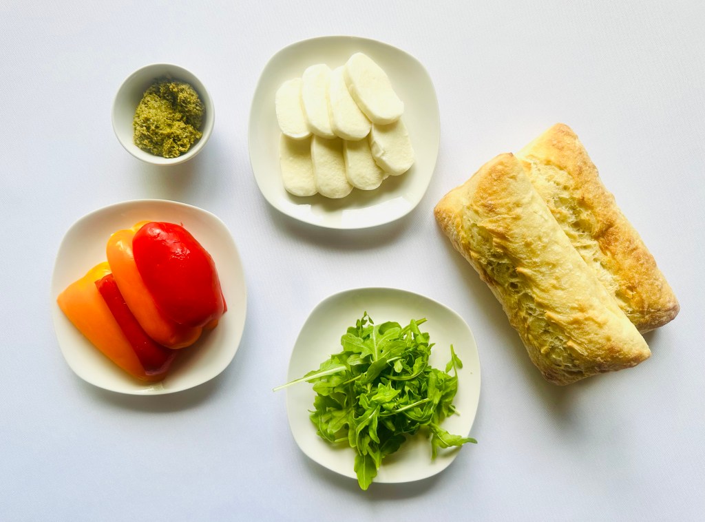 A photo of ingredients used to make roasted pepper, mozzarella, and pesto sandwiches