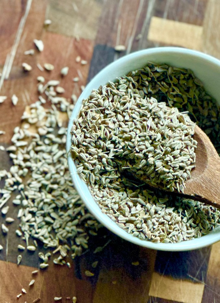 A photo of anise seeds being scooped up in a bowl