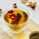 A clear mug full of freshly brewed anise seed tea with cinnamon sticks and edible flowers